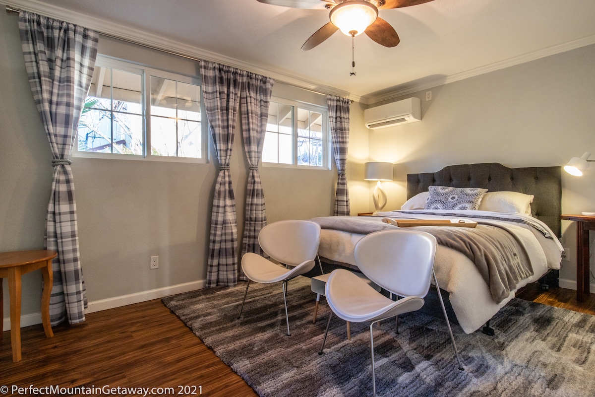 Bedroom with a large bed, two chairs, and plaid curtains.