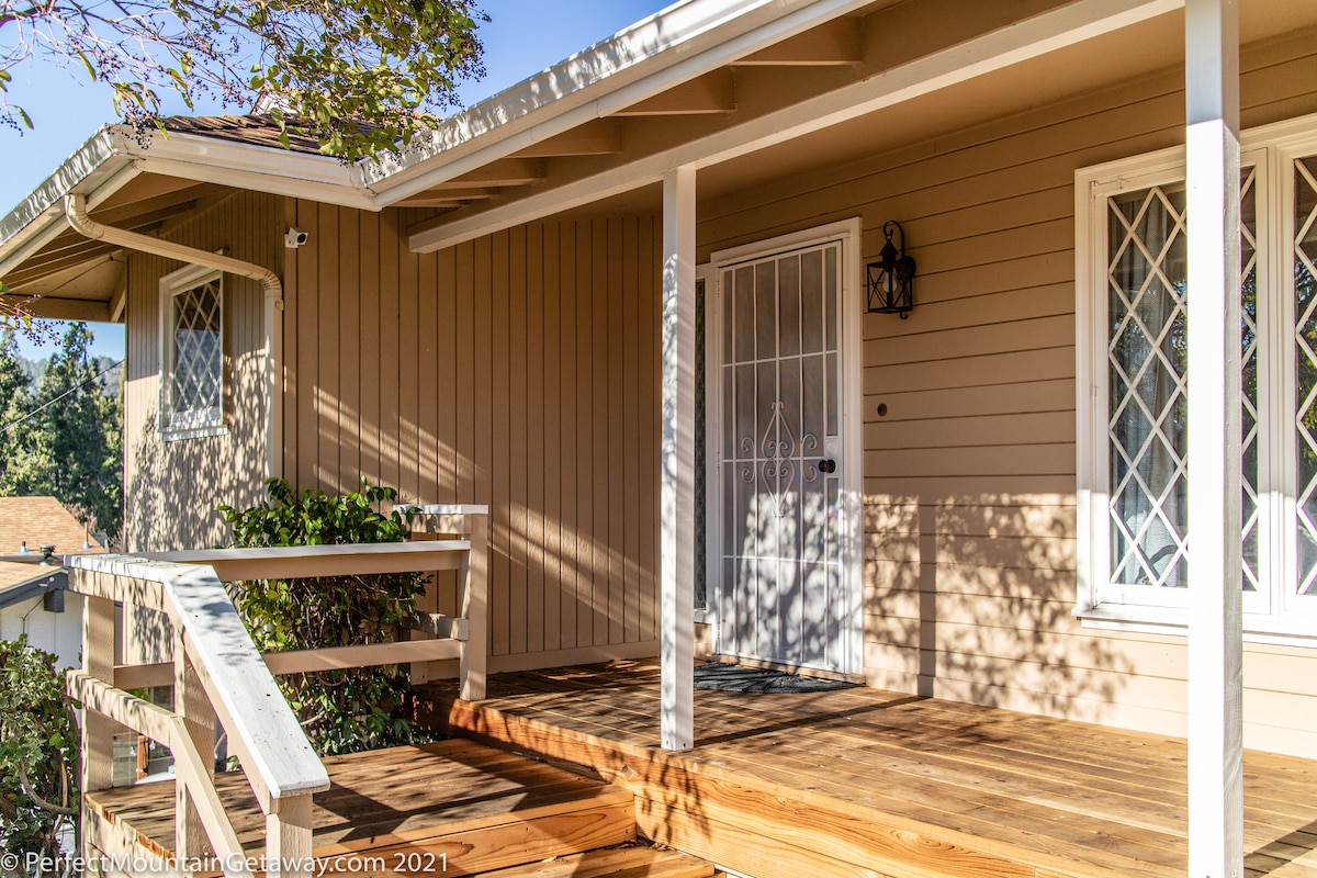 Wooden front porch with white railing and door.
