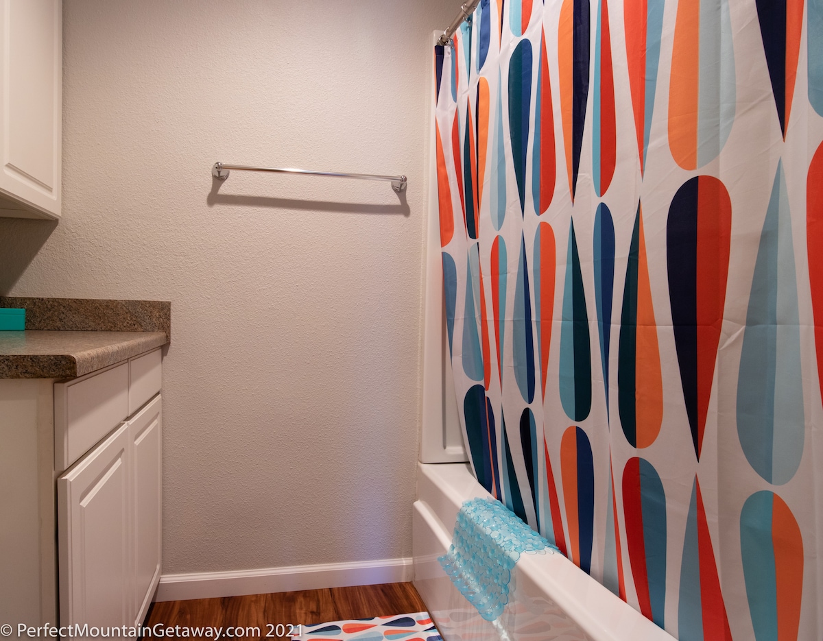 Bathroom with colorful shower curtain and white vanity.