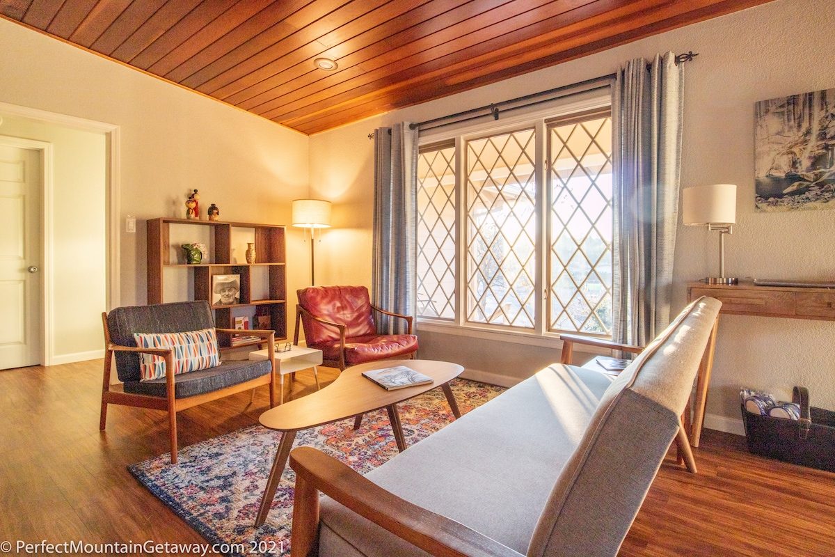 Sunlit living room with wooden furniture and large window.